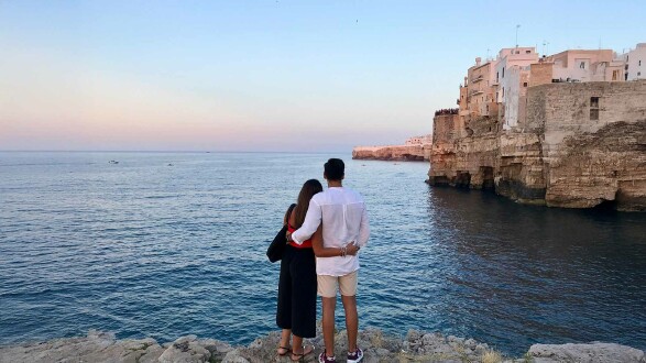 Paar blickt auf das Meer vor malerischen Felsklippen in Italien – Tipps zur sicheren Urlaubsbuchung für unbeschwerte Reisen.