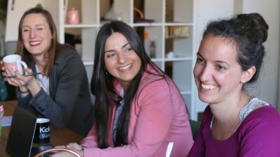 Drei Frauen sitzen an einem Tisch mit Laptops