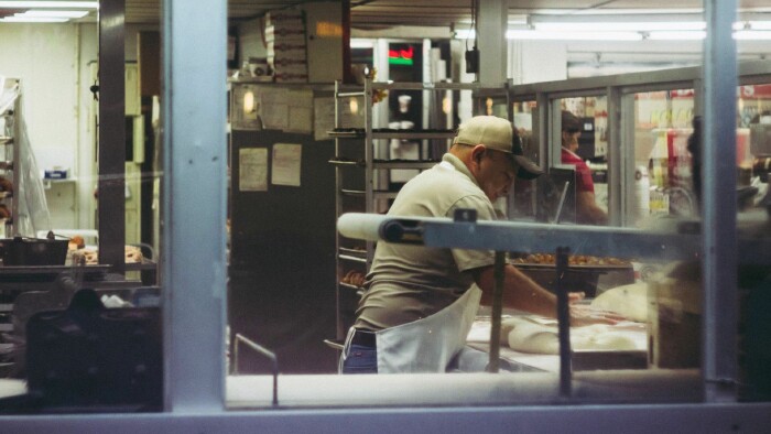 Person steht an einer Theke und bearbeitet Teig