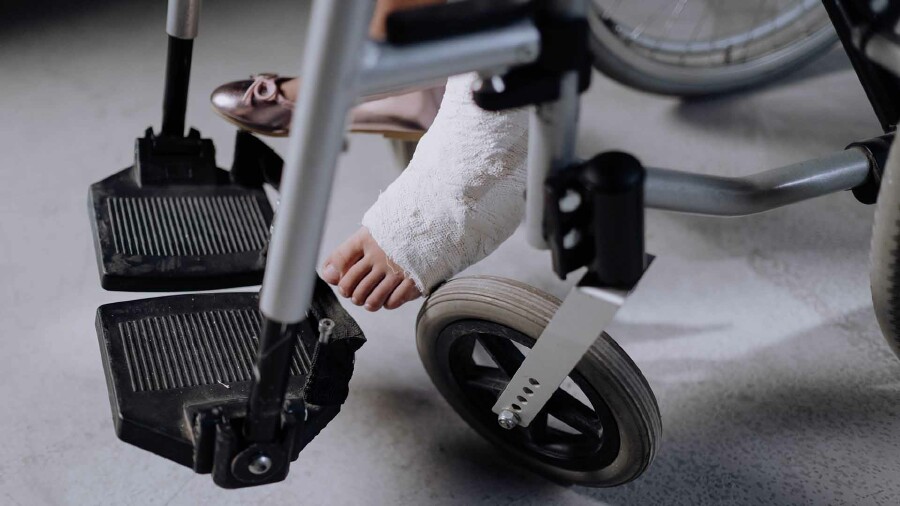 Ein eingegipster Fuß in einem Rollstuhl.