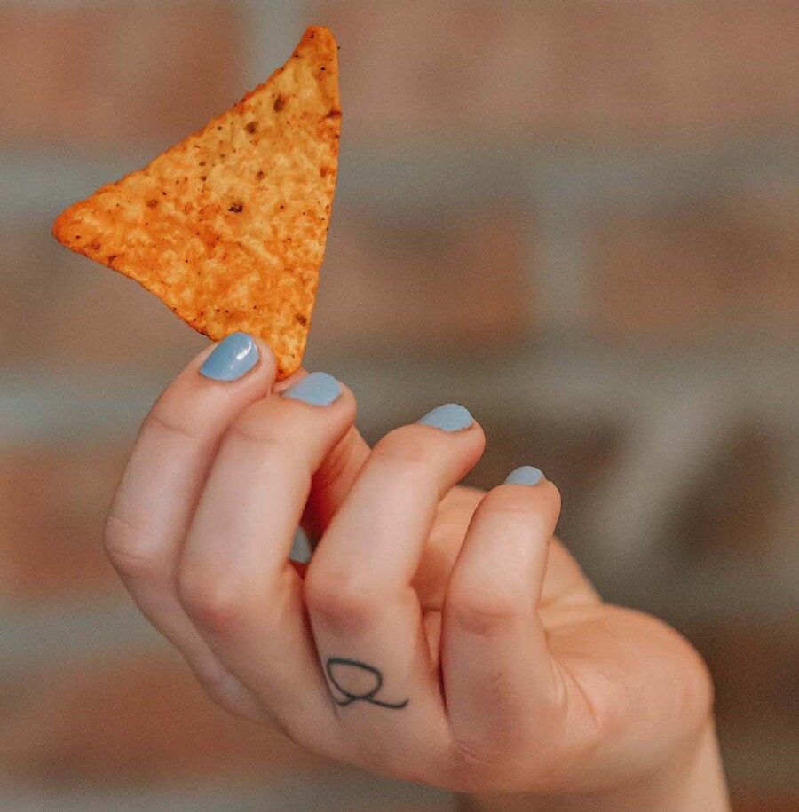 Eine Hand hält einen Tortilla-Chip.