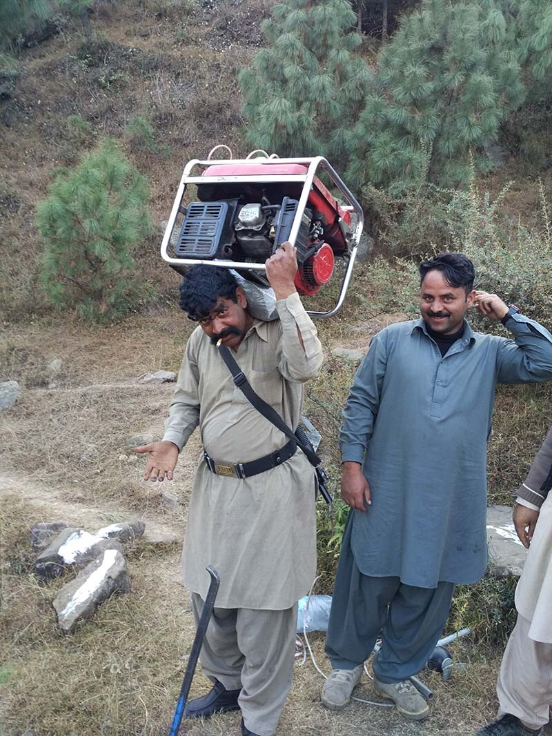 Die Helfer in Pakistan beschützten Elmar Röck und sein Team nicht nur, sie bestanden auch darauf, deren Werkzeuge zu tragen. © Elmar Röck Ein Mann trägt einen schweren Generator auf dem Rücken.