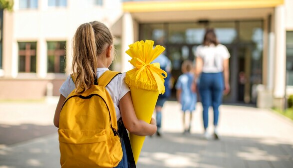  Kind mit gelber Schult&uuml;te auf dem Schulhof
