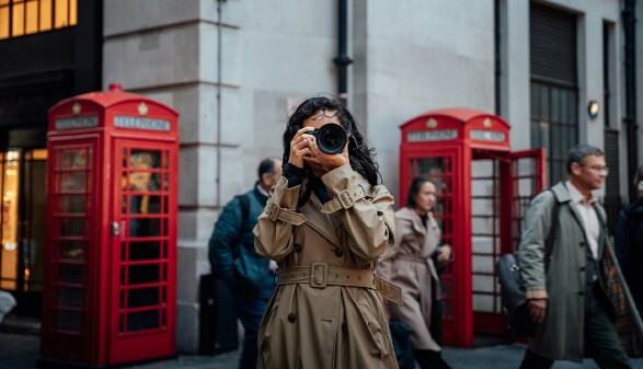Touristin fotografiert in London vor roten Telefonzellen – Symbolbild für Großbritannien Urlaub 2025 und neue ETA-Einreisebestimmungen