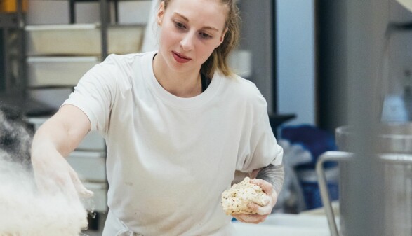 Bäckerin bei der nächtlichen Teigzubereitung in professioneller Backstube – engagierte Handarbeit, während andere schlafen, für frisches Brot am Morgen.