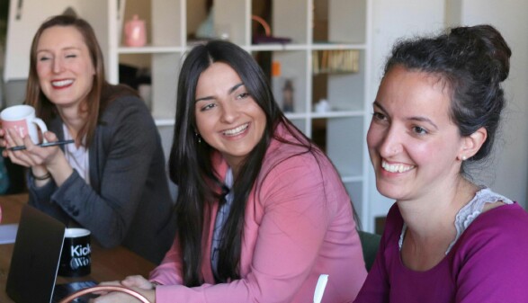 Drei Frauen sitzen an einem Tisch mit Laptops