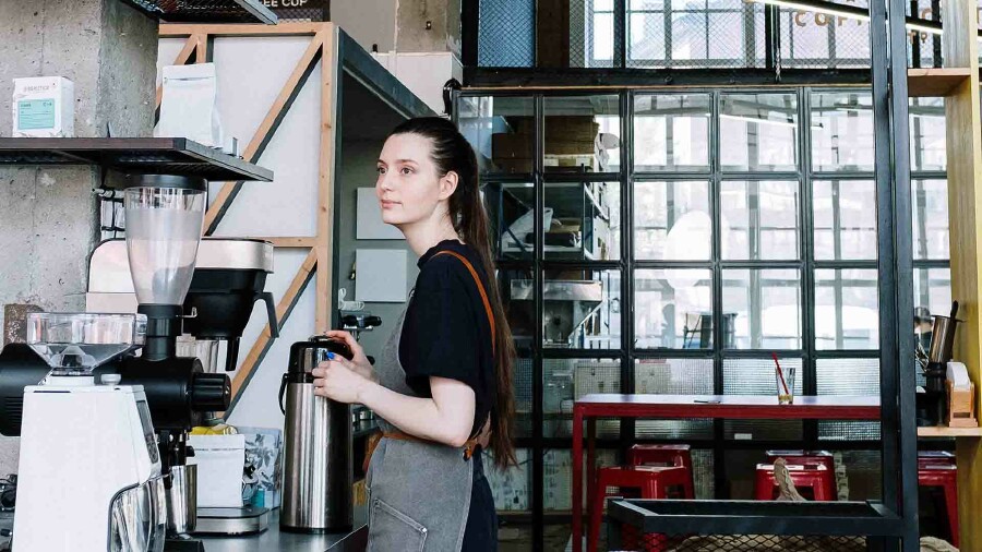 Eine junge Frau bedient eine Kaffeemaschine.